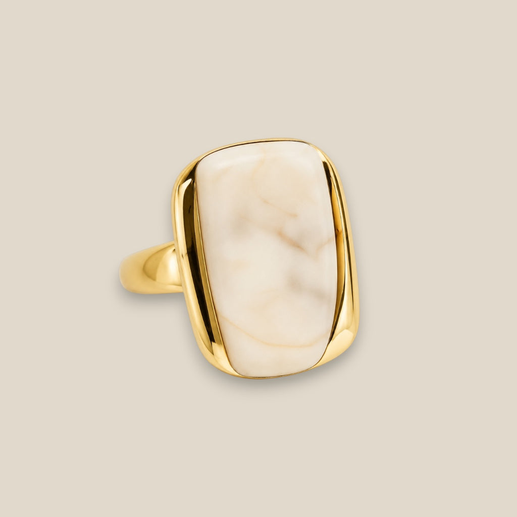 Anillo Eterna de acero dorado con piedra de vetas naturales, diseño ajustable, sobre fondo neutro