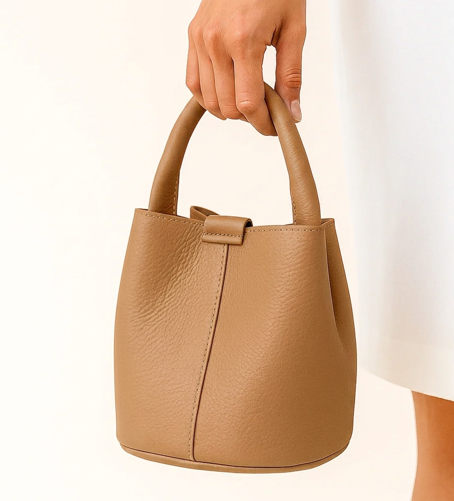 Bolso Bombonera Valeria camel de piel granulada sostenido en mano, detalle del asa y cierre