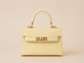 Bolso Kelly amarillo de piel estructurado con asa corta y detalles metálicos dorados, vista frontal