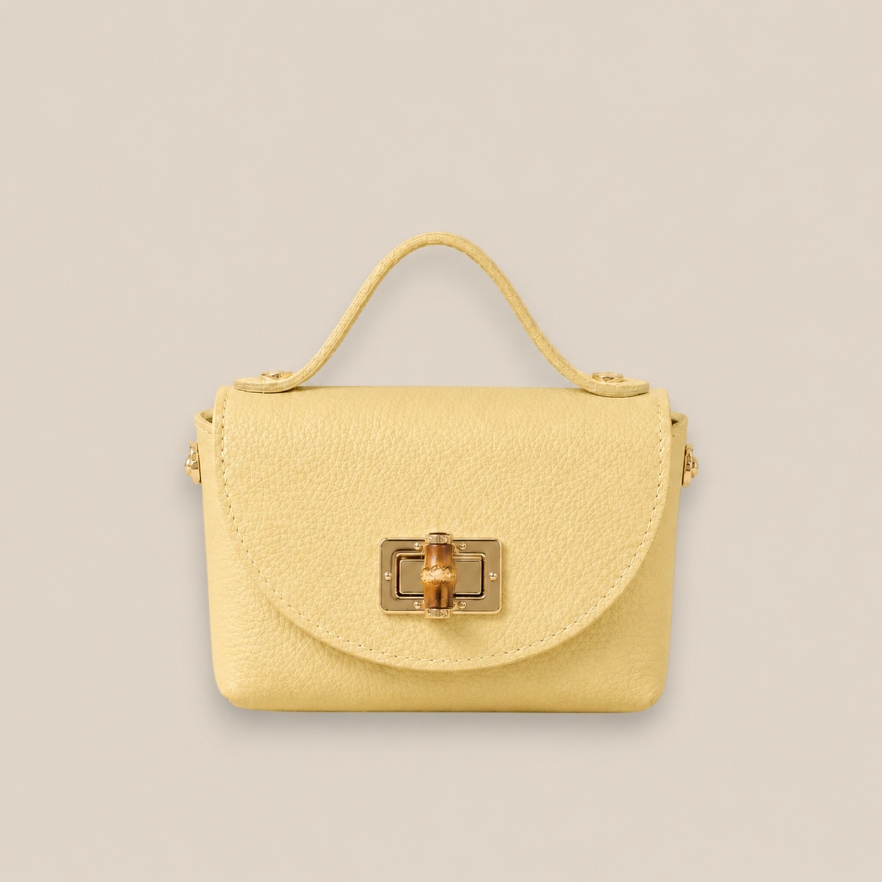 Bolso de piel amarillo con solapa redondeada, broche metálico dorado y detalle central de bambú
