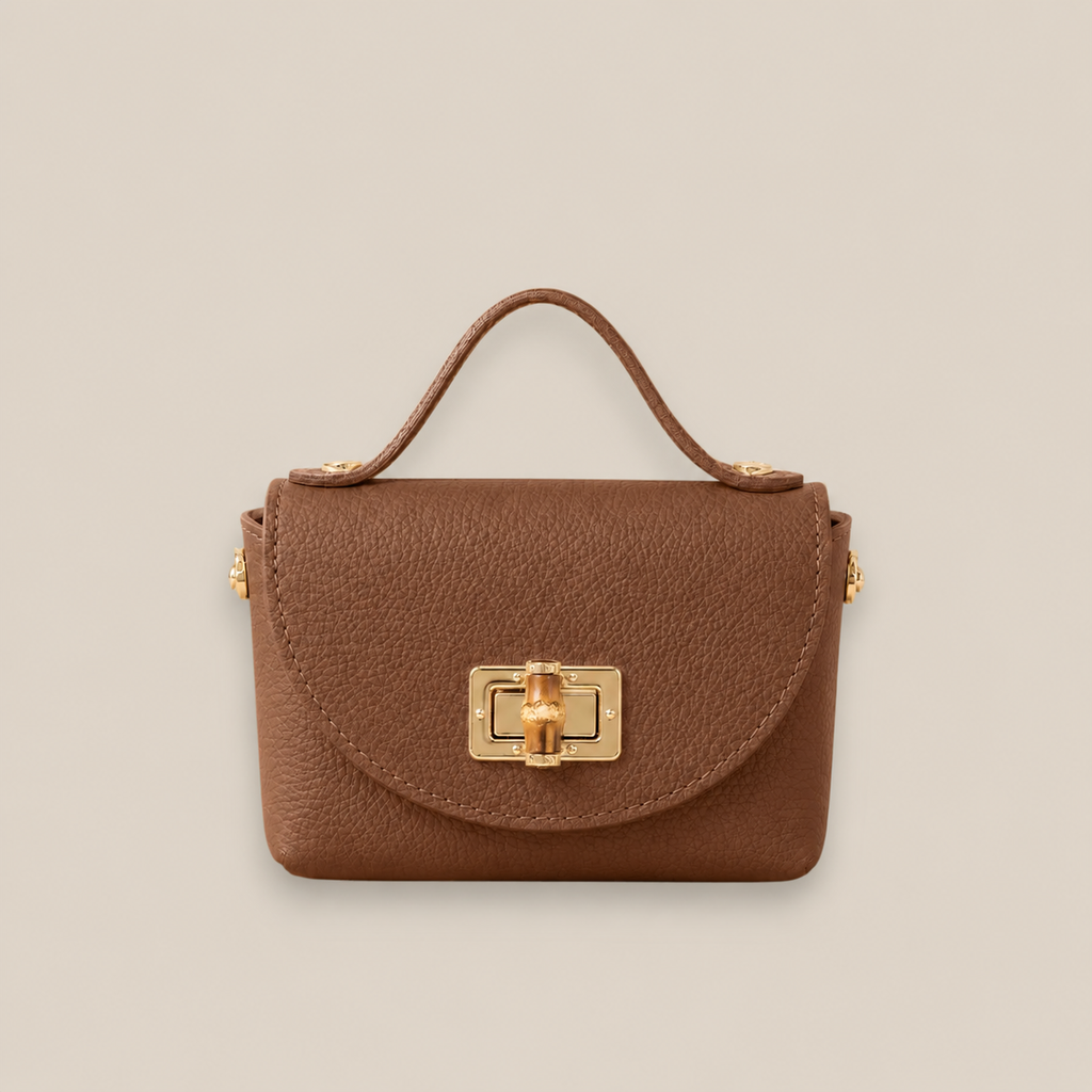Bolso de piel camel con solapa redondeada, broche metálico dorado y detalle central de bambú