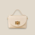 Bolso de piel crema con solapa redondeada, broche metálico dorado y detalle central de bambú