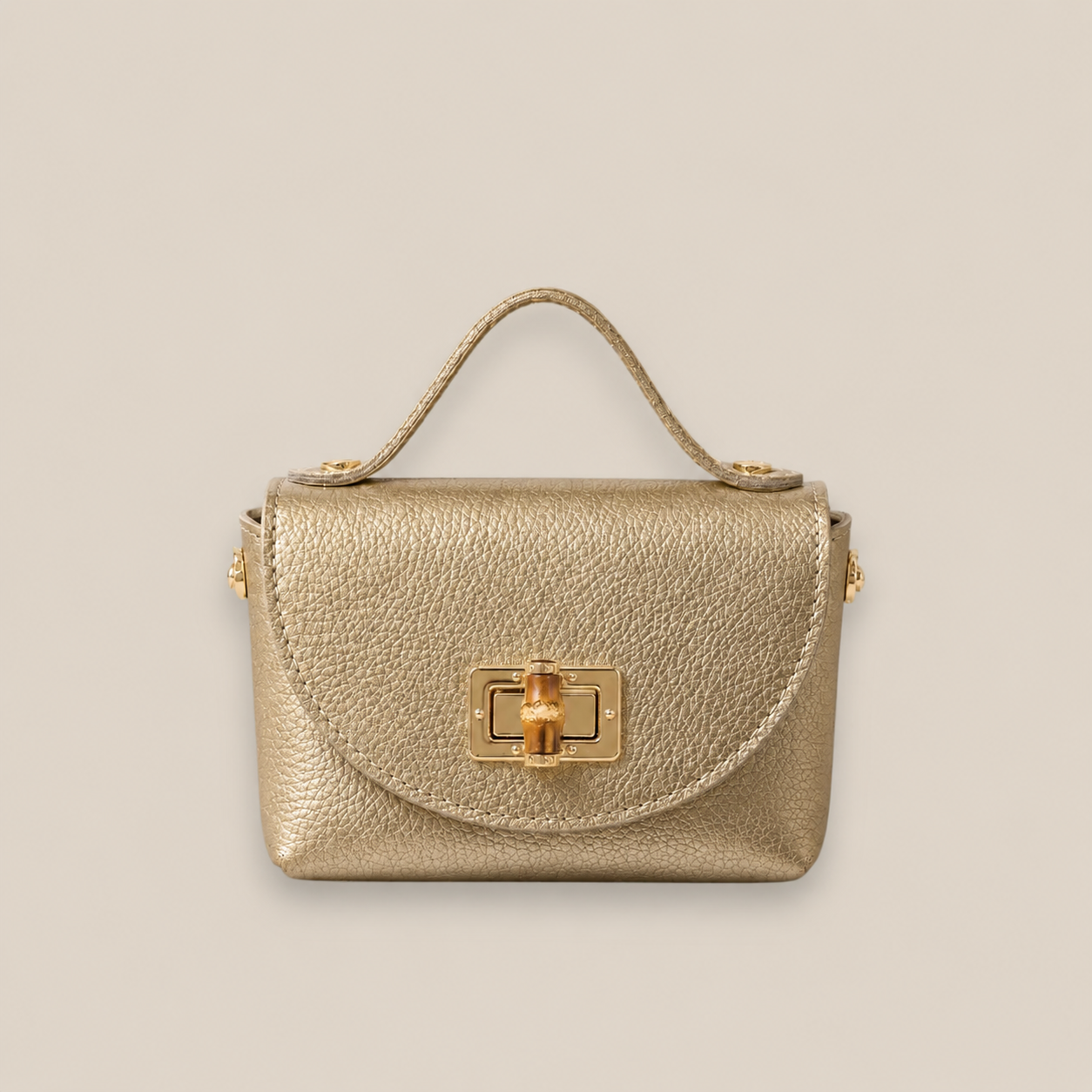 Bolso de piel dorado con solapa redondeada, broche metálico dorado y detalle central de bambú