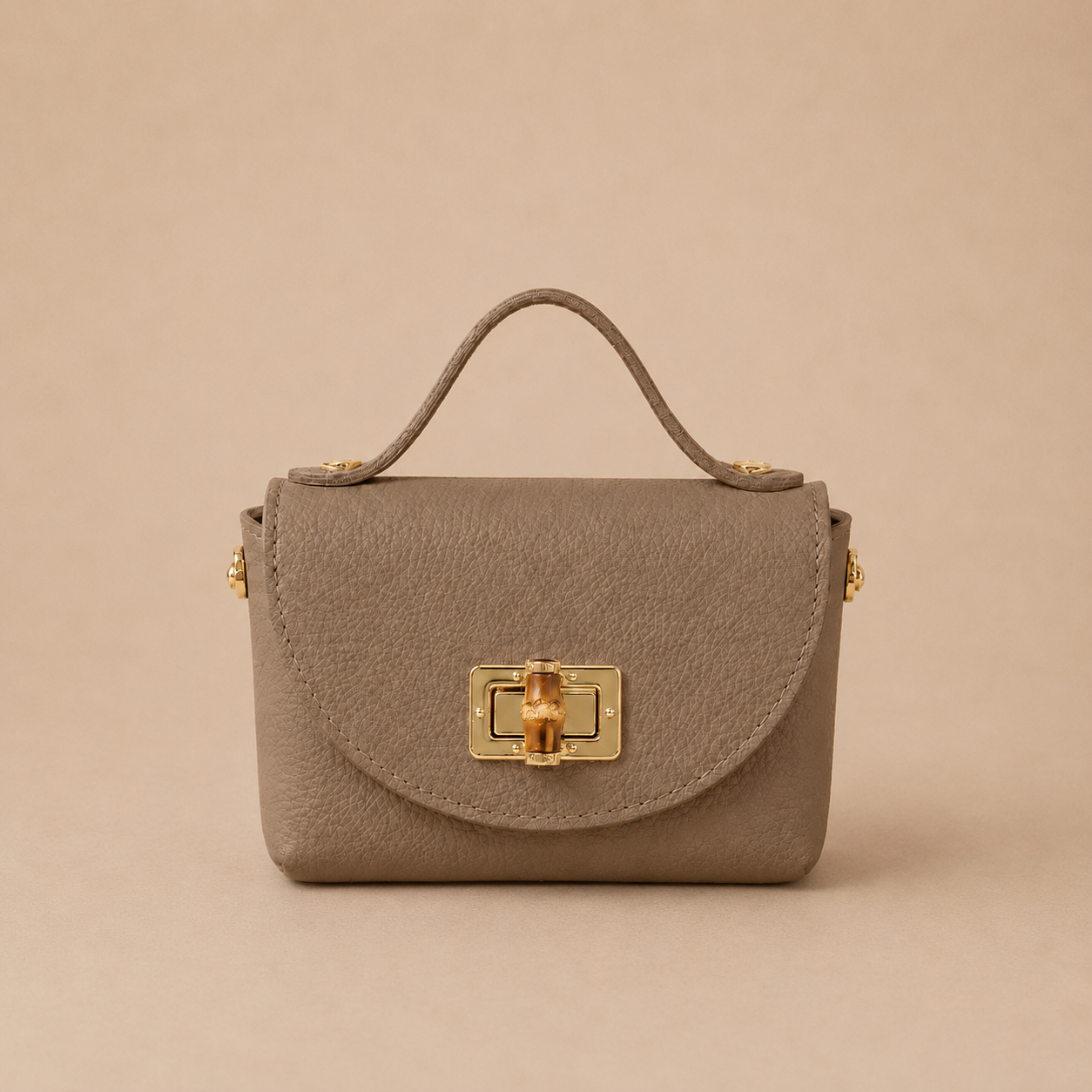Bolso de piel taupe con solapa redondeada, broche metálico dorado y detalle
