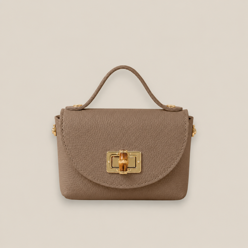 Bolso de piel taupe con solapa redondeada, broche metálico dorado y detalle central de bambú