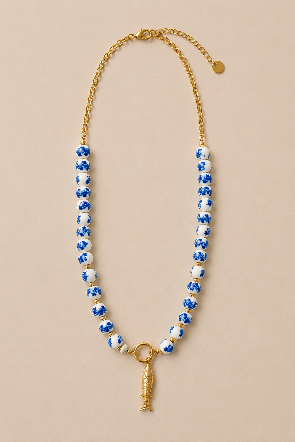 Collar de cuentas de porcelana con detalles y colgante de pez en acero inoxidable dorado.
