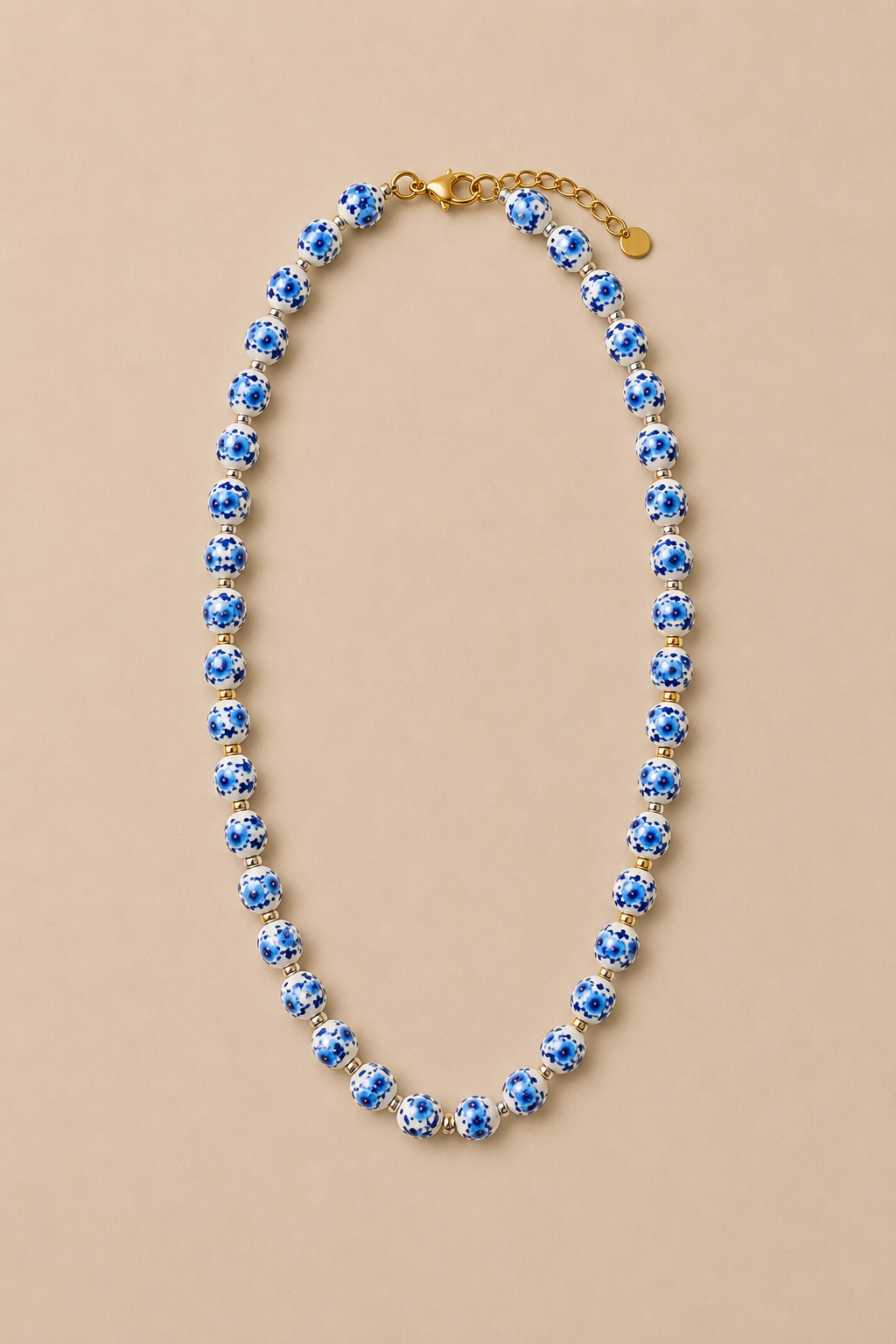 Collar de cuentas  medianas de porcelana con detalles y colgante de pez en acero inoxidable dorado.