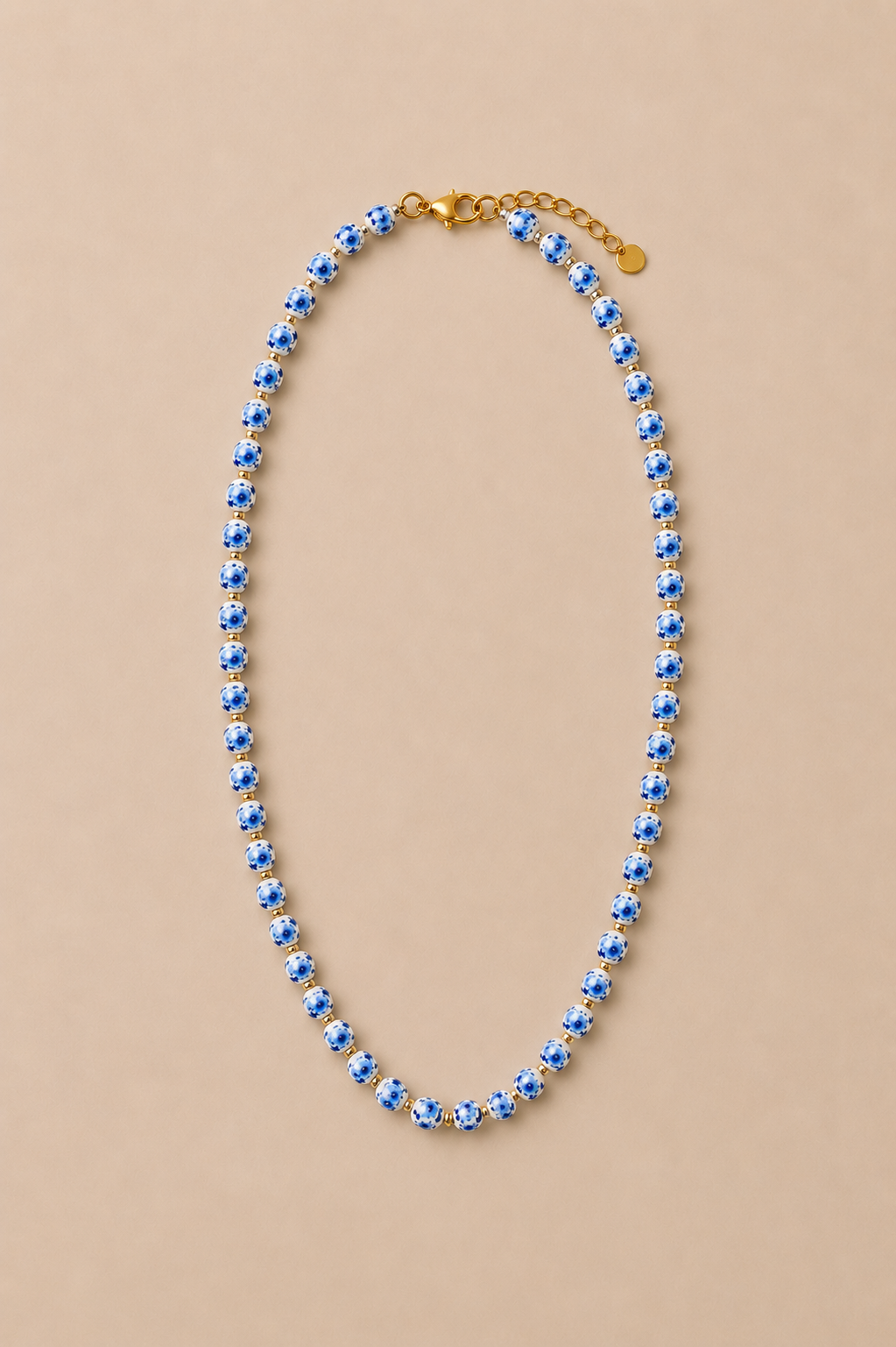 Collar de cuentas pequeñas de porcelana con detalles y colgante de pez en acero inoxidable dorado.