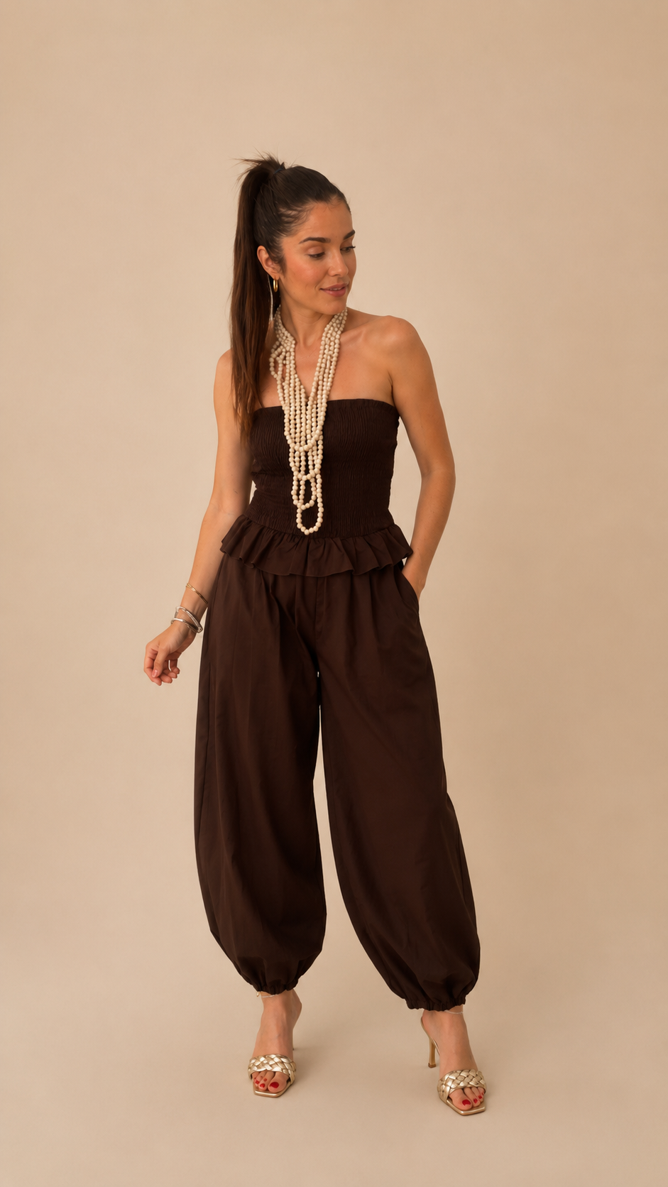 Modelo con Mono Kenia marrón chocolate, top bandeau fruncido sin tirantes y pantalón harem abullonado, 