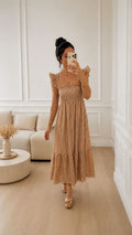 Modelo con Vestido Vichy Beige de cuadros blancos y beige, fruncido en el pecho, tirantes de volantes y largo favorecedor