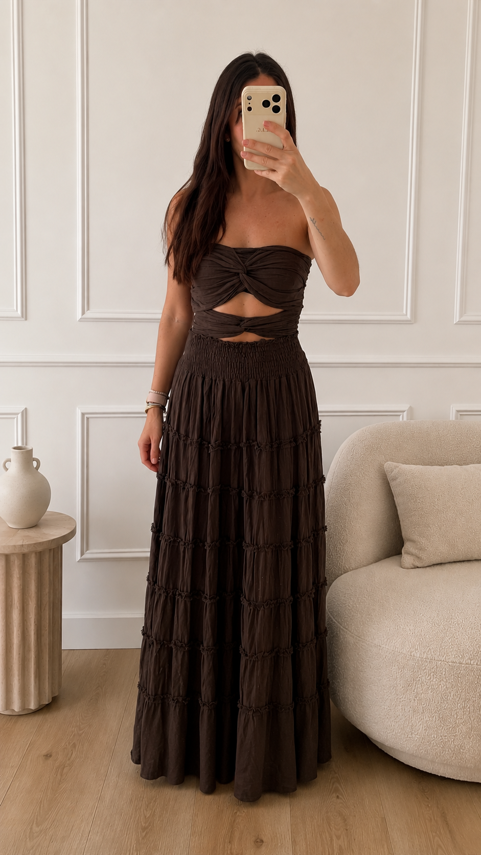 Modelo vistiendo el Vestido Gala marron chocolate, diseño strapless con nudo frontal y falda larga escalonada con volantes en algodón natural. Talla única equivalente a tallas 34-38.
