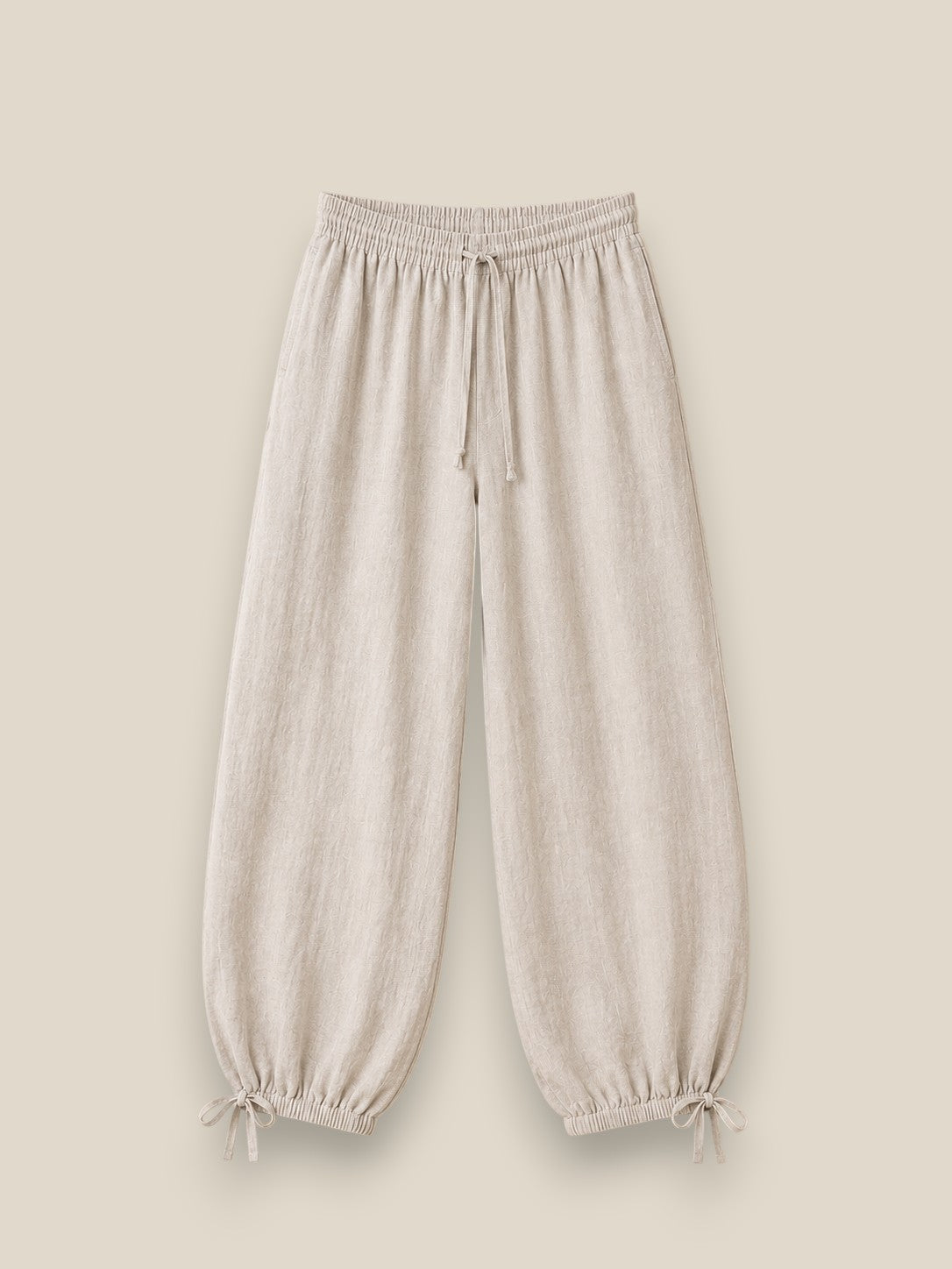 Pantalón bombacho de lino en color beige topo con cintura elástica, lazadas ajustables en el bajo y tejido ligero de estilo mediterráneo