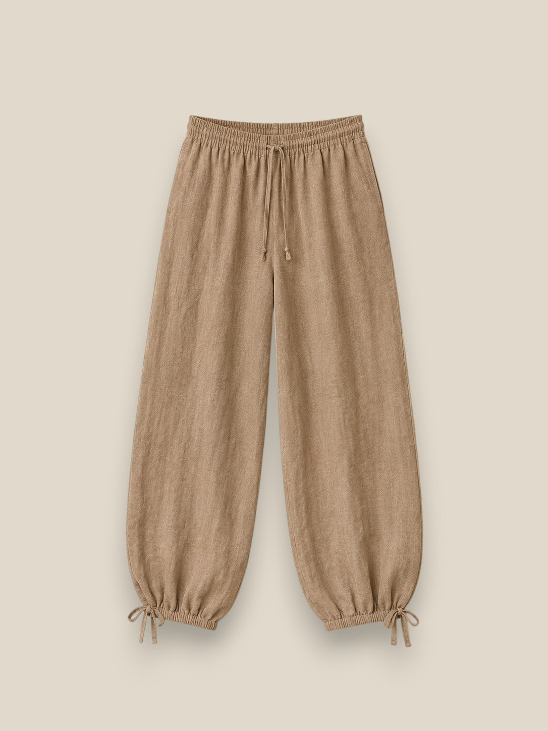 Pantalón bombacho de lino en color beige topo con cintura elástica, lazadas ajustables en el bajo y tejido ligero de estilo mediterráneo