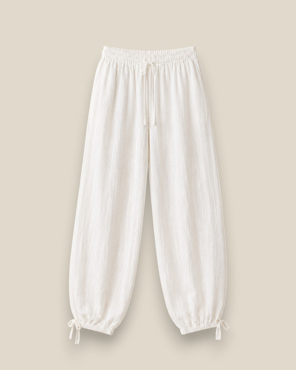 Pantalón bombacho de lino en color blanco topo con cintura elástica, lazadas ajustables en el bajo y tejido ligero de estilo mediterráneo
