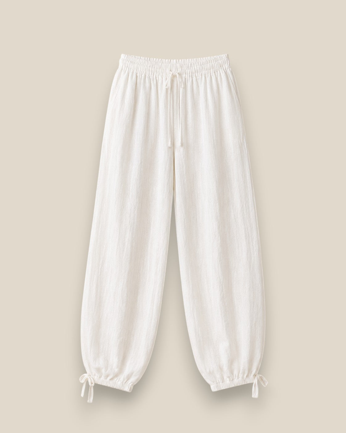 Pantalón bombacho de lino en color blanco topo con cintura elástica, lazadas ajustables en el bajo y tejido ligero de estilo mediterráneo