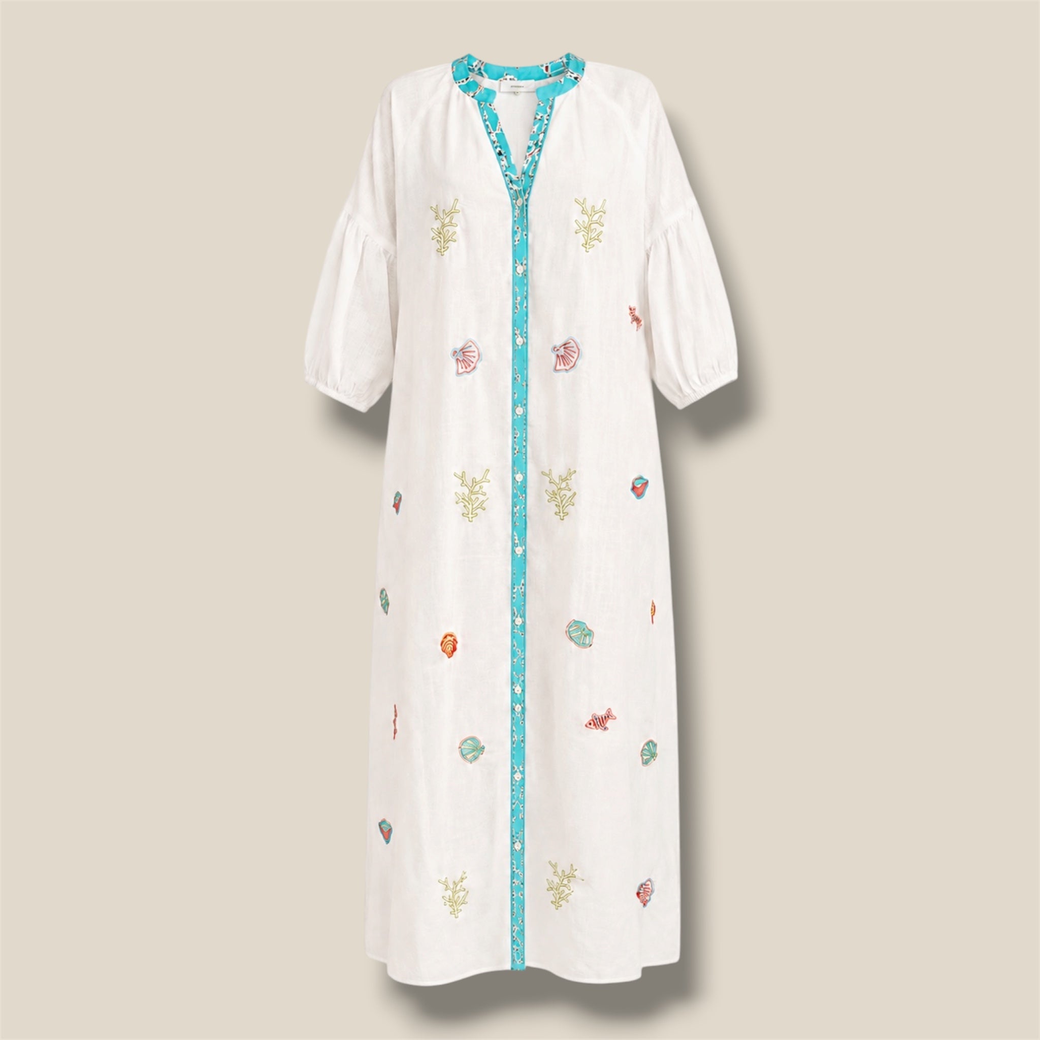 Vestido Océano blanco de Quiérete Muxo con bordados marinos de coral, conchas y peces en verde y turquesa.