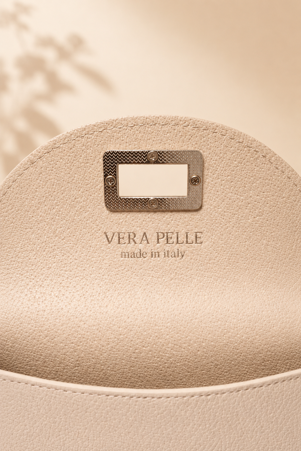 nterior del bolso de piel crema con compartimentos y acabados en tono dorado